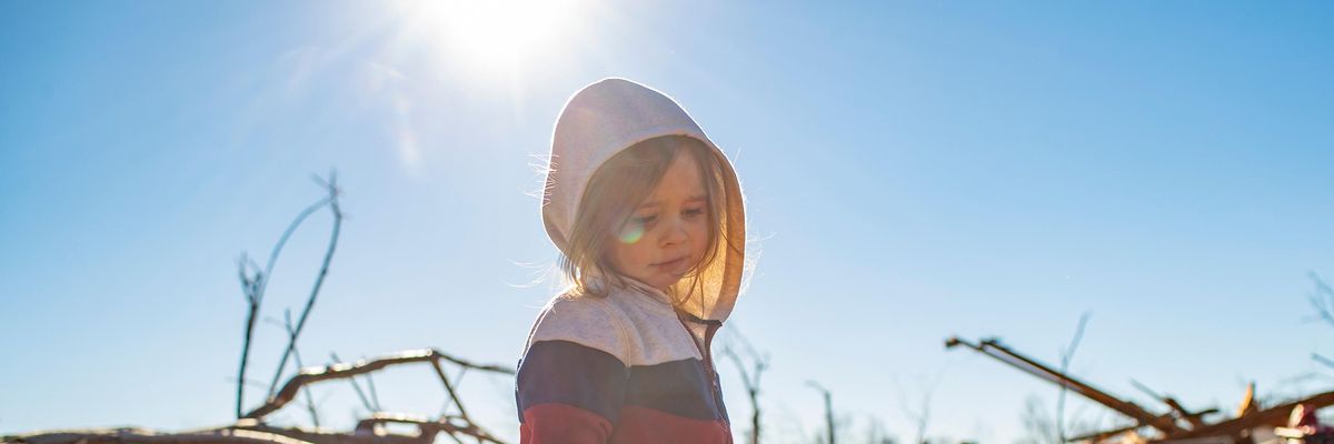 A child stands amid the rubble left by a devastating tornado system.