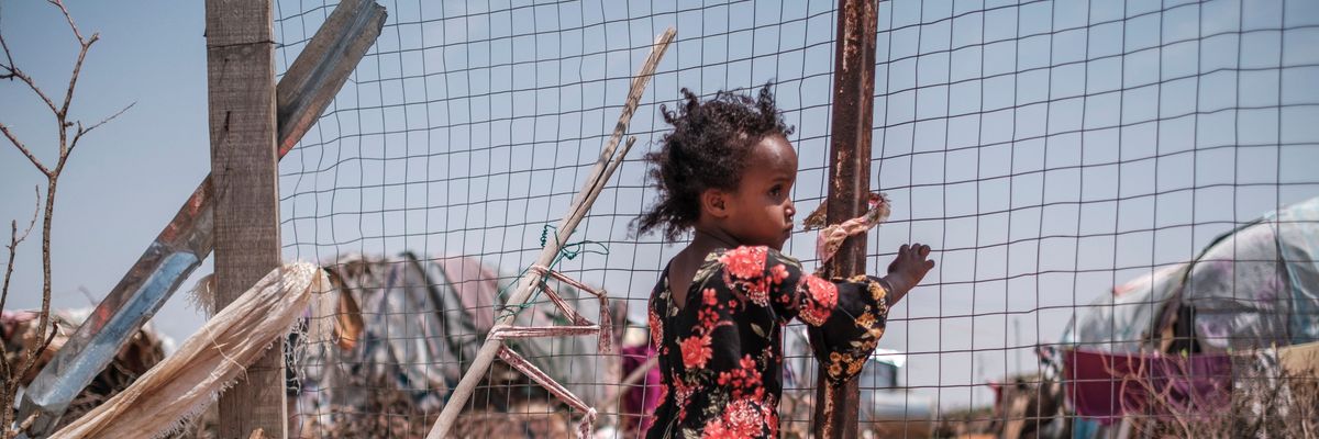 A child stands near an informal settlement