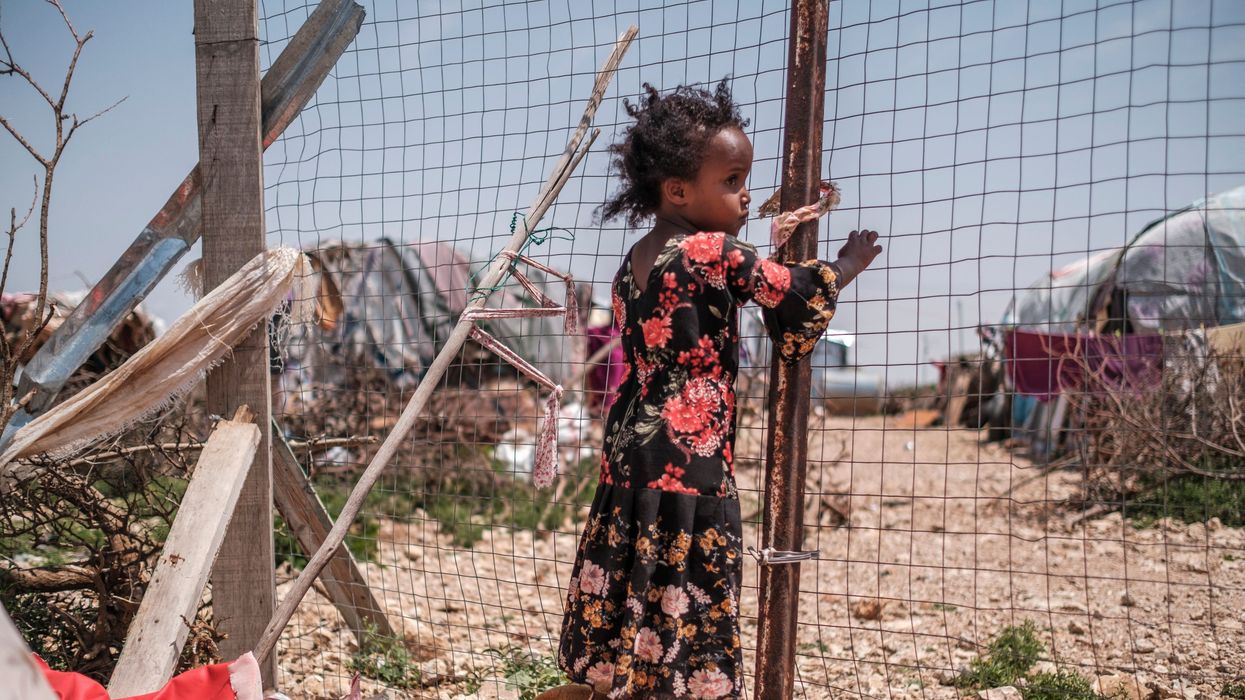 A child stands near an informal settlement