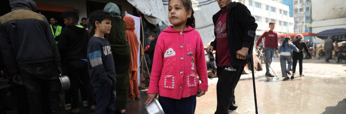 A child waits with an empty pot