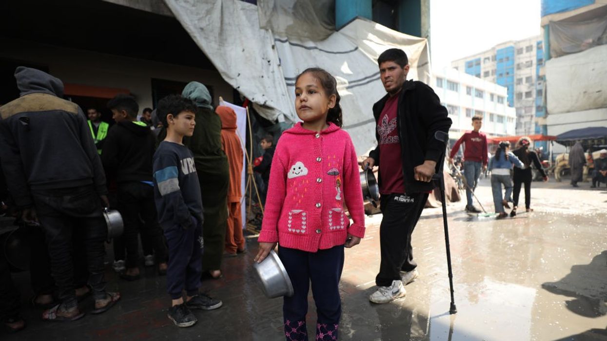 A child waits with an empty pot