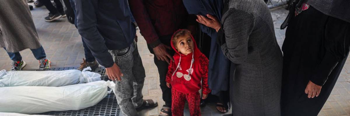 A child watches as a mourner cries over bodies