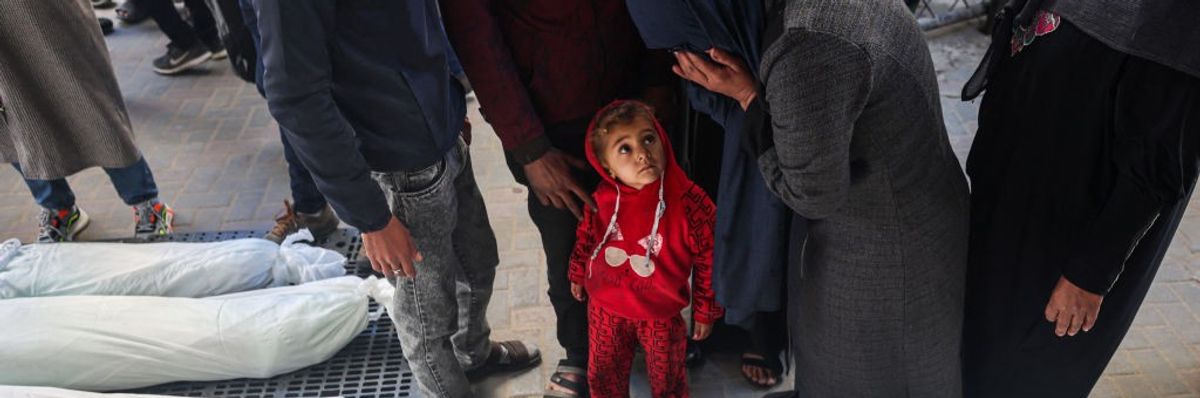 A child watches as a mourner cries over bodies