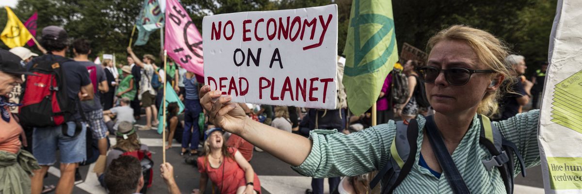 A climate activist holds a sign reading "No economy on a dead planet,"