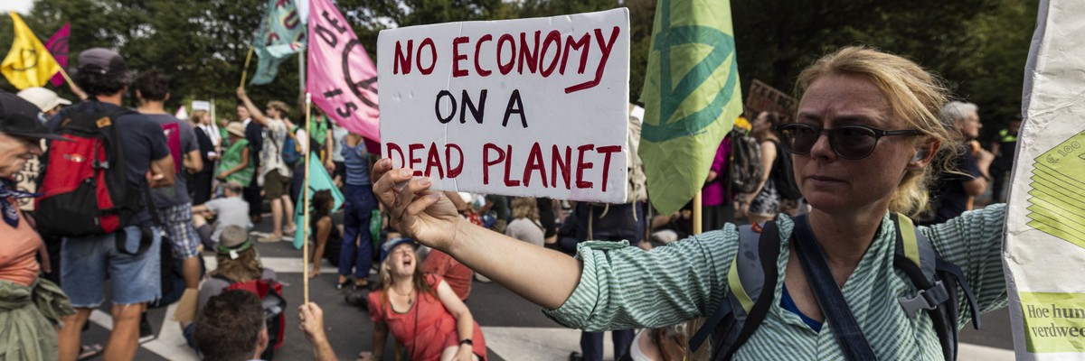 A climate activist holds a sign reading "No economy on a dead planet,"