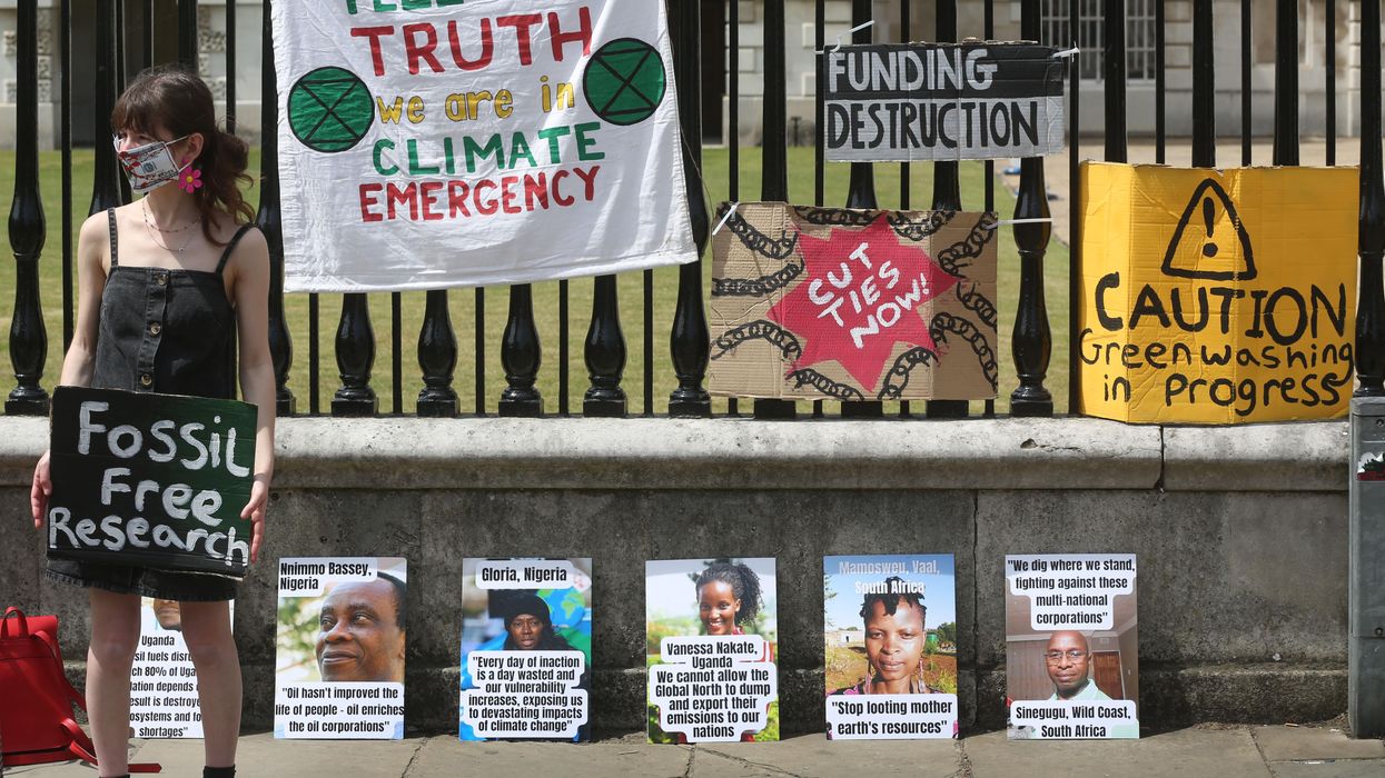 A climate activist holds a sign saying 'Fossil Free Research' outside Cambridge University on June 16, 2022.