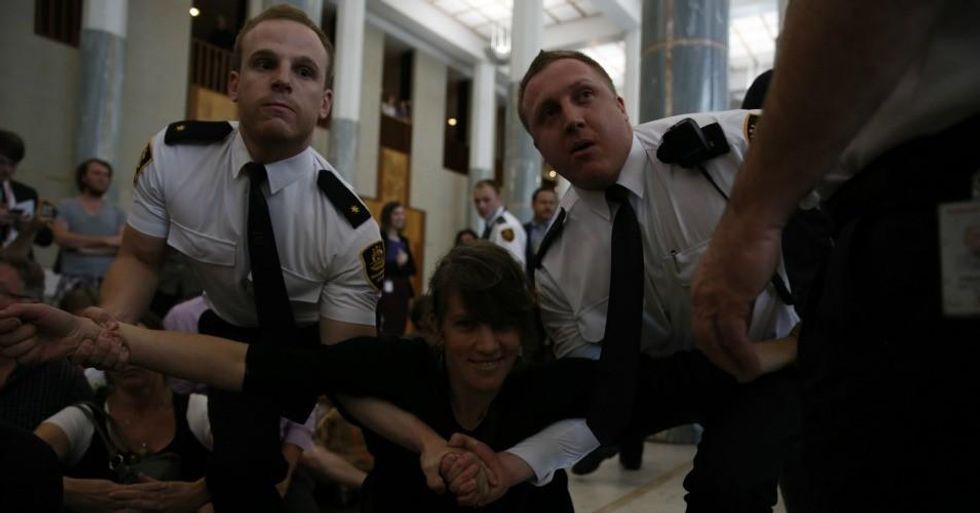 A climate protesters is dragged away by security officers.  (Photo:350 .org/flickr/cc)