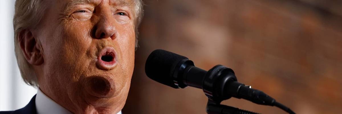 A close-up of Donald Trump speaking into a microphone.