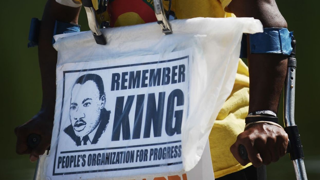 A closeup of a sign worn by a demonstrator reading, "Remember King."