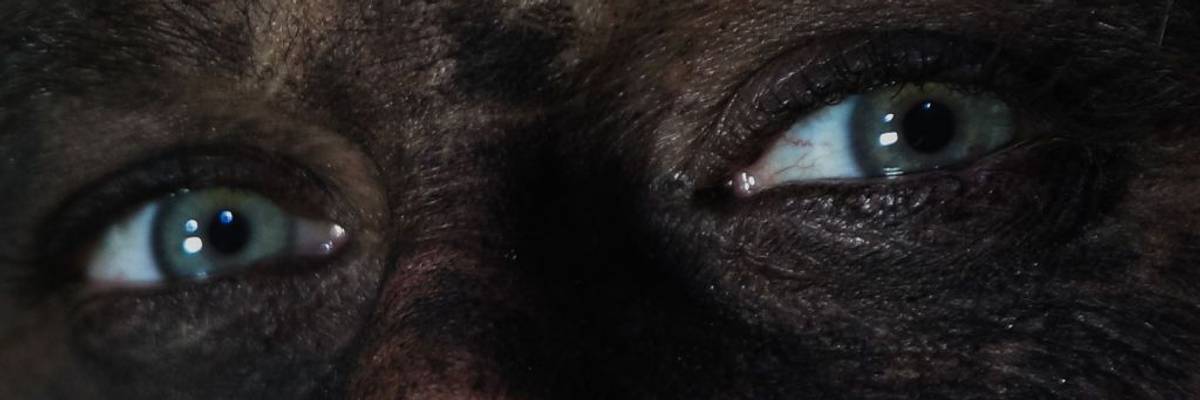 A coal miner's face is covered in dust