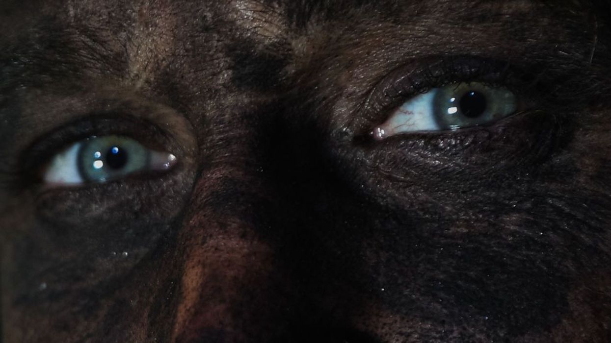 A coal miner's face is covered in dust