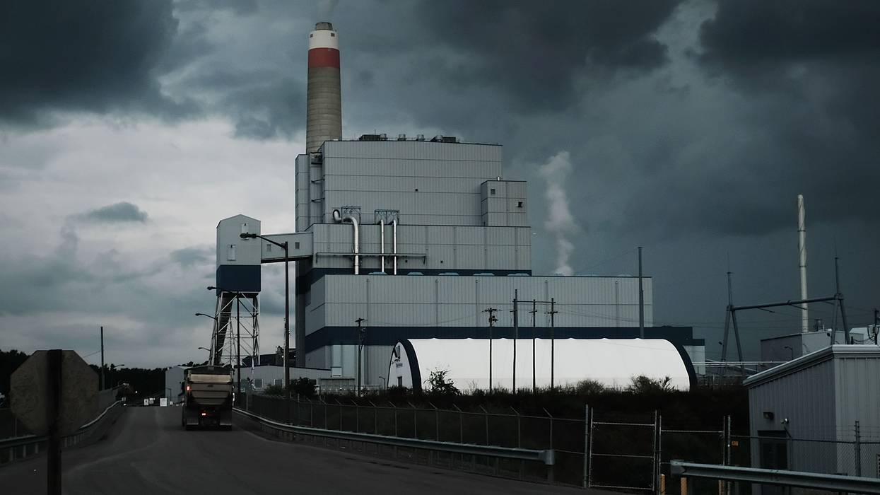 A coal power plant emits smoke against a cloudy sky.