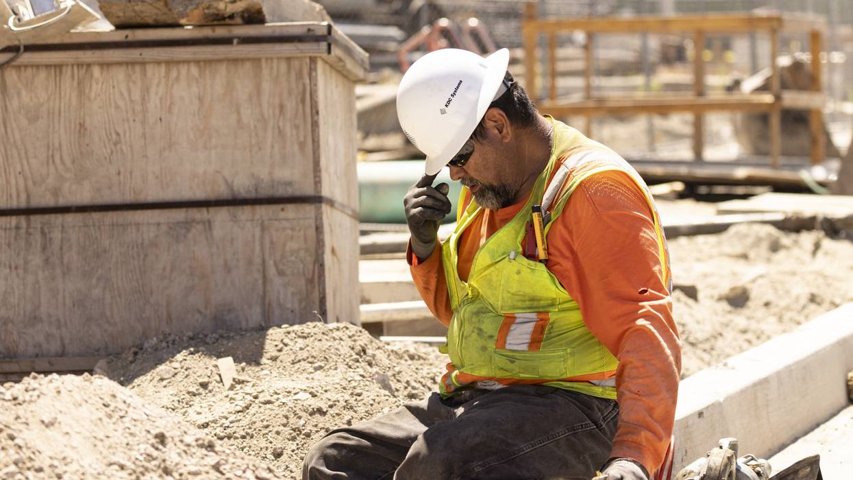A construction worker adjusts his hard hat during a heatwave.