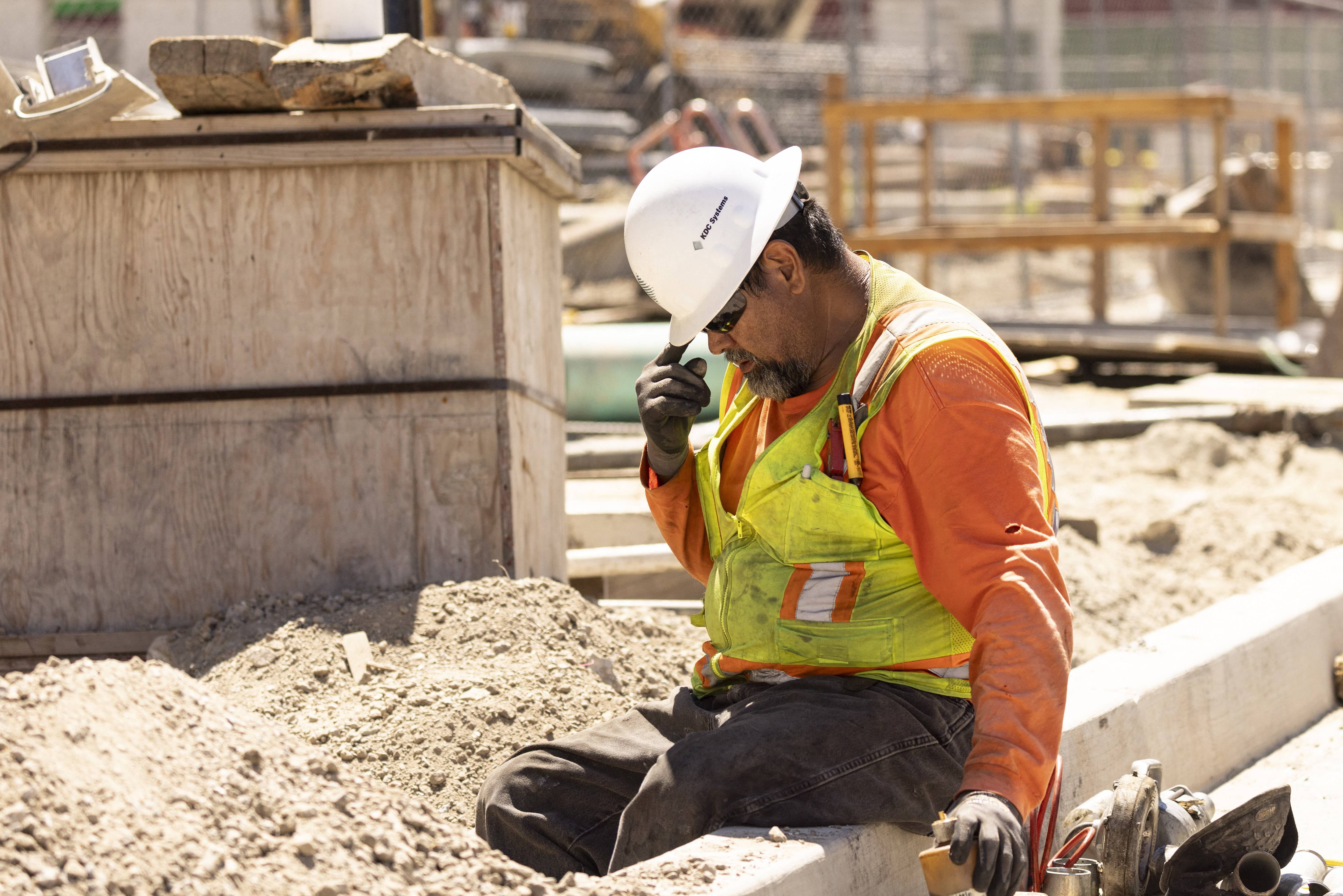 A construction worker adjusts his hard hat during a heatwave.