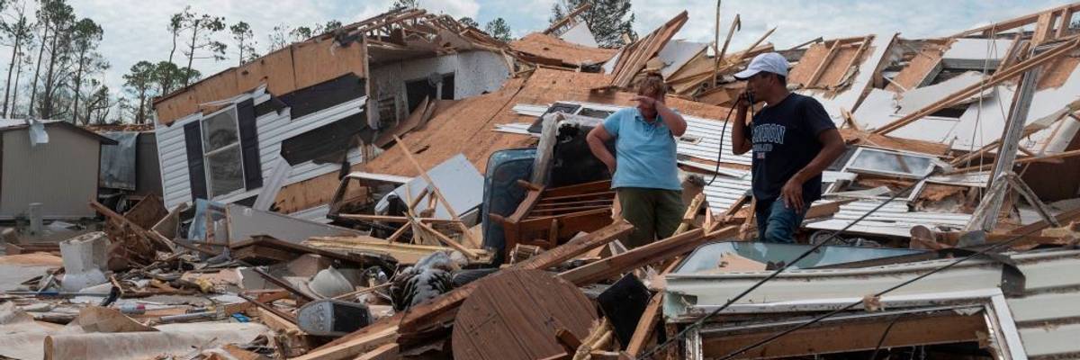 A couple stands in the ruins of their mobile home after a hurricane.