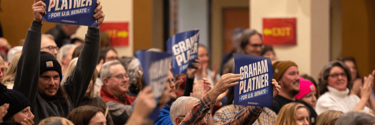 A crowd holds up "Graham Platner for US Senate" signs