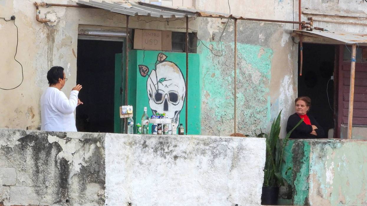 A Cuban woman sells drinks outside her home.
