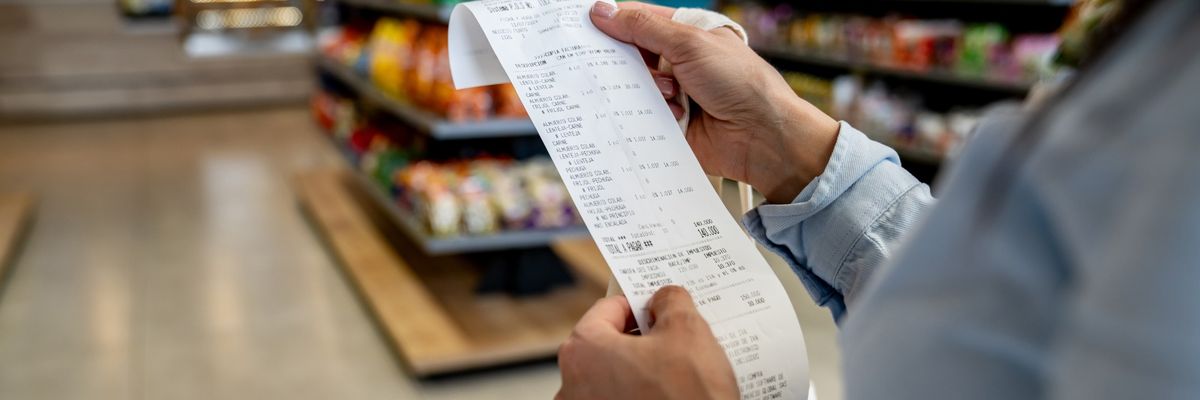 A customer holds a paper receipt in a supermarket
