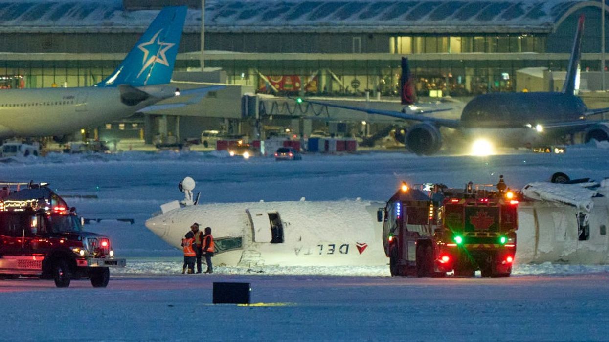 A Delta plane lies upside down on a runway at Toronto's airport after a crash