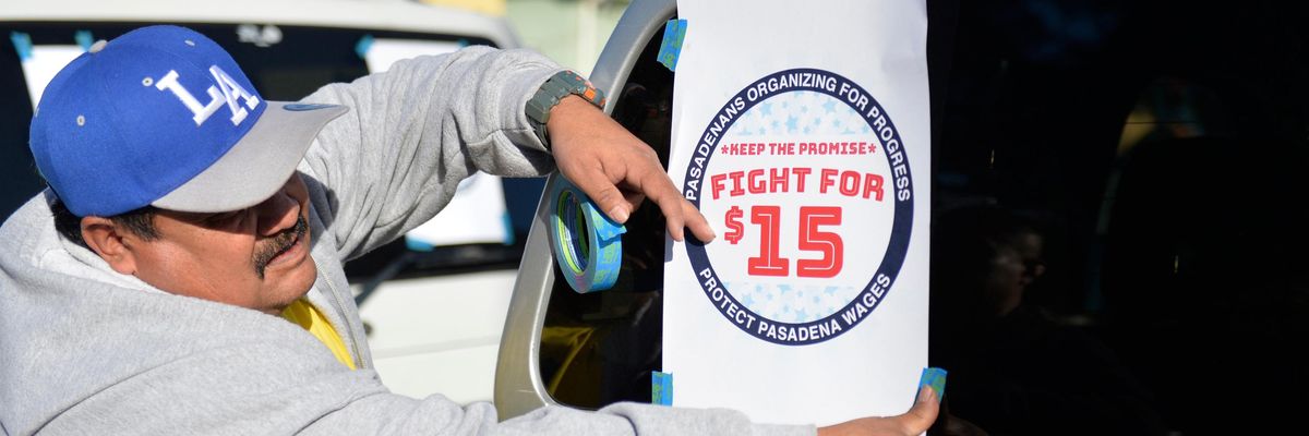 A demonstrator attaches a "Fight for $15" sign to his truck
