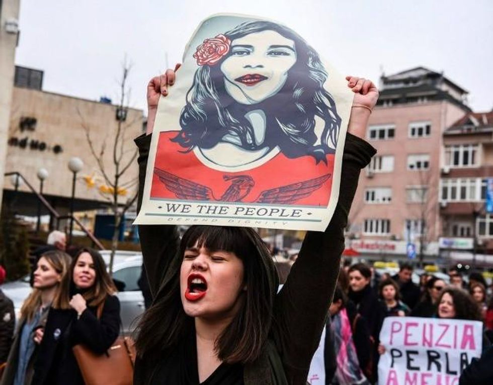 A demonstrator hods up a Shepard Fairey sign in Kosovo. (Photo: Getty)
