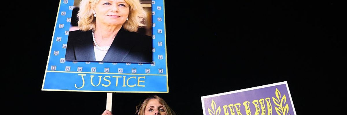 A demonstrator holds a placard with an image of Israeli Attorney General Gali Baharav-Miara