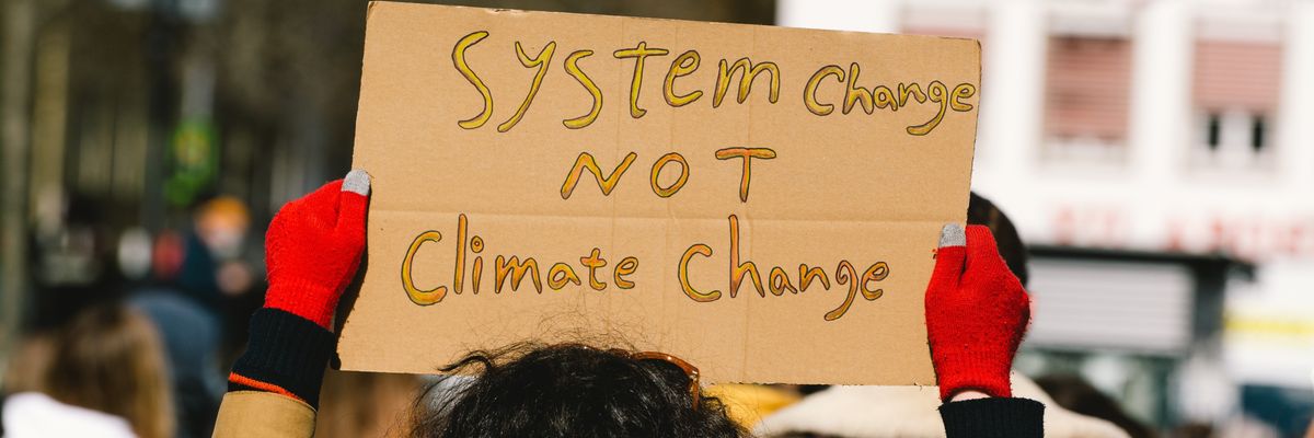 A demonstrator holds a poster demanding "system change not climate change" during a global march organized by Fridays for Future in Cologne, Germany on March 19, 2021.