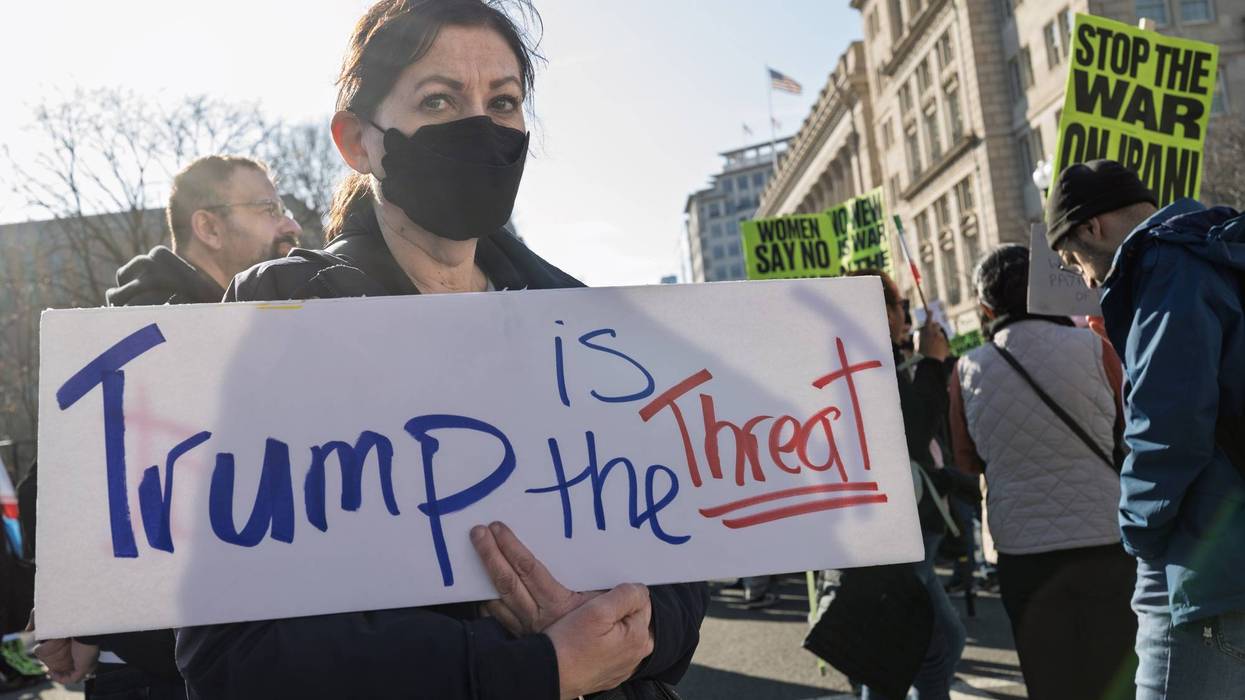 A demonstrator holds a sign reading "Trump is the threat