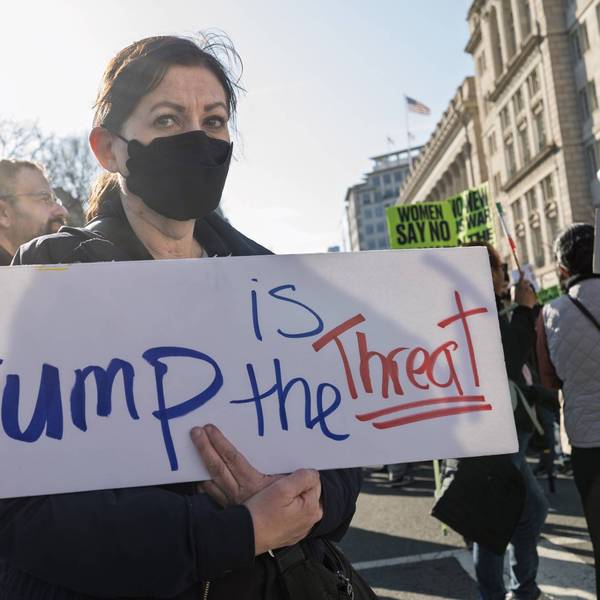 A demonstrator holds a sign reading "Trump is the threat