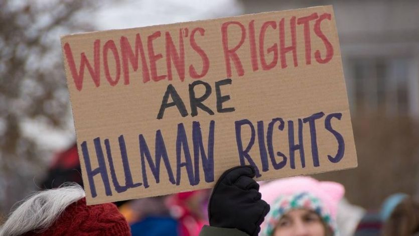 A demonstrator holds a sign reading, “Women’s rights are human rights.”