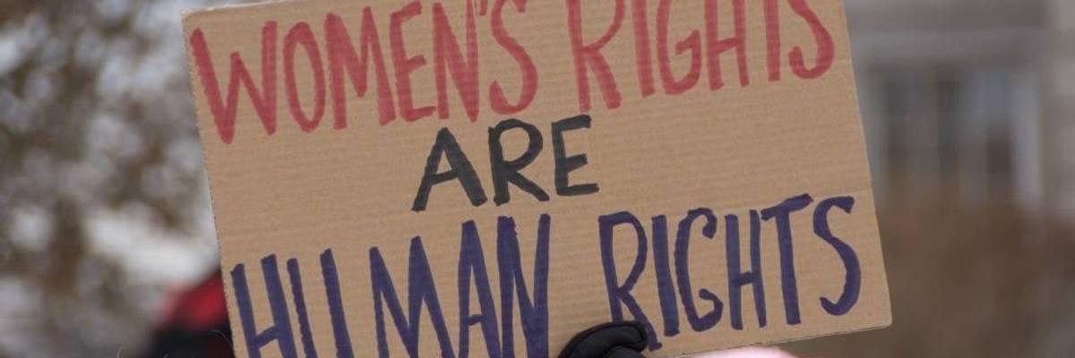 A demonstrator holds a sign reading, “Women’s rights are human rights.”