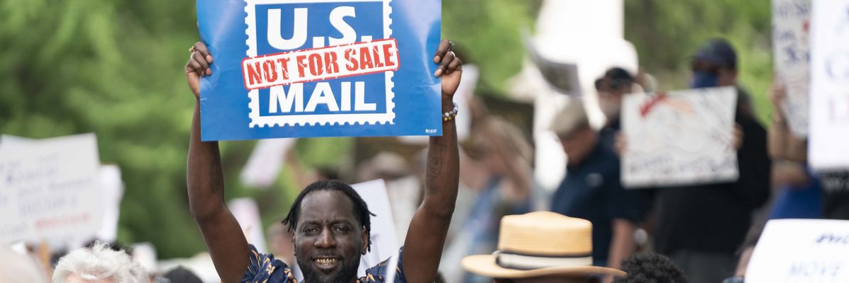 A demonstrator holds a sign supporting the United States Postal Service