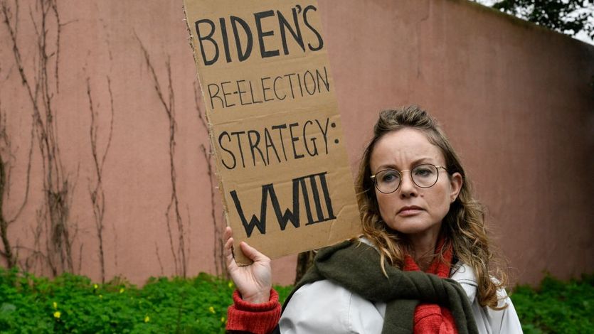 A demonstrator holds a sign that says "Biden's reelection strategy: WWIII" 