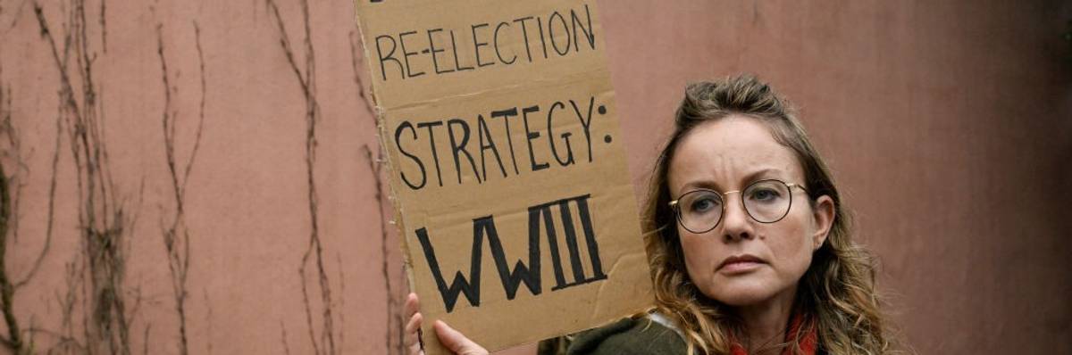 A demonstrator holds a sign that says "Biden's reelection strategy: WWIII"