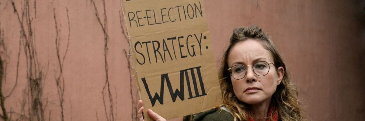 A demonstrator holds a sign that says "Biden's reelection strategy: WWIII"