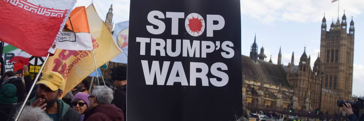 A demonstrator holds a 'Stop Trump's Wars' placard