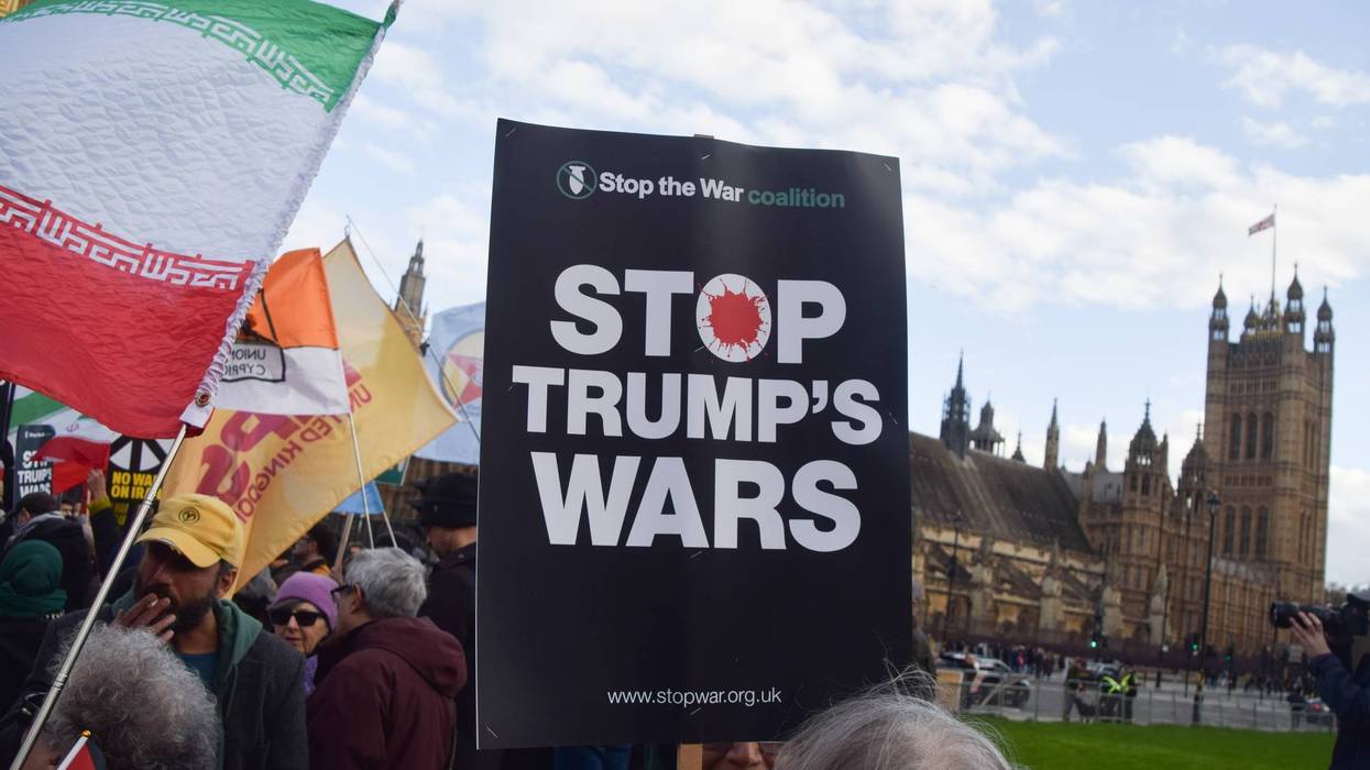 A demonstrator holds a 'Stop Trump's Wars' placard