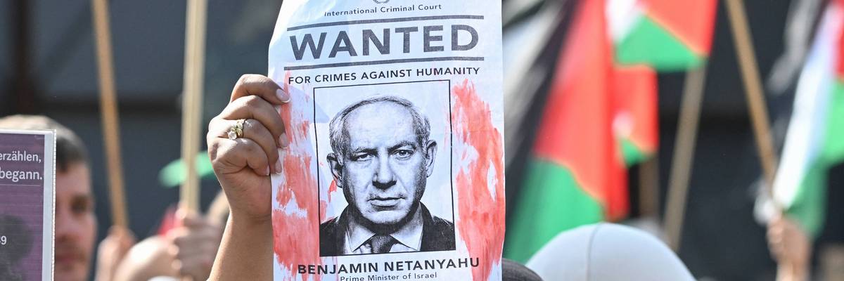 A demonstrator holds up a "Wanted" poster featuring Israeli Prime Minister Benjamin Netanyahu
