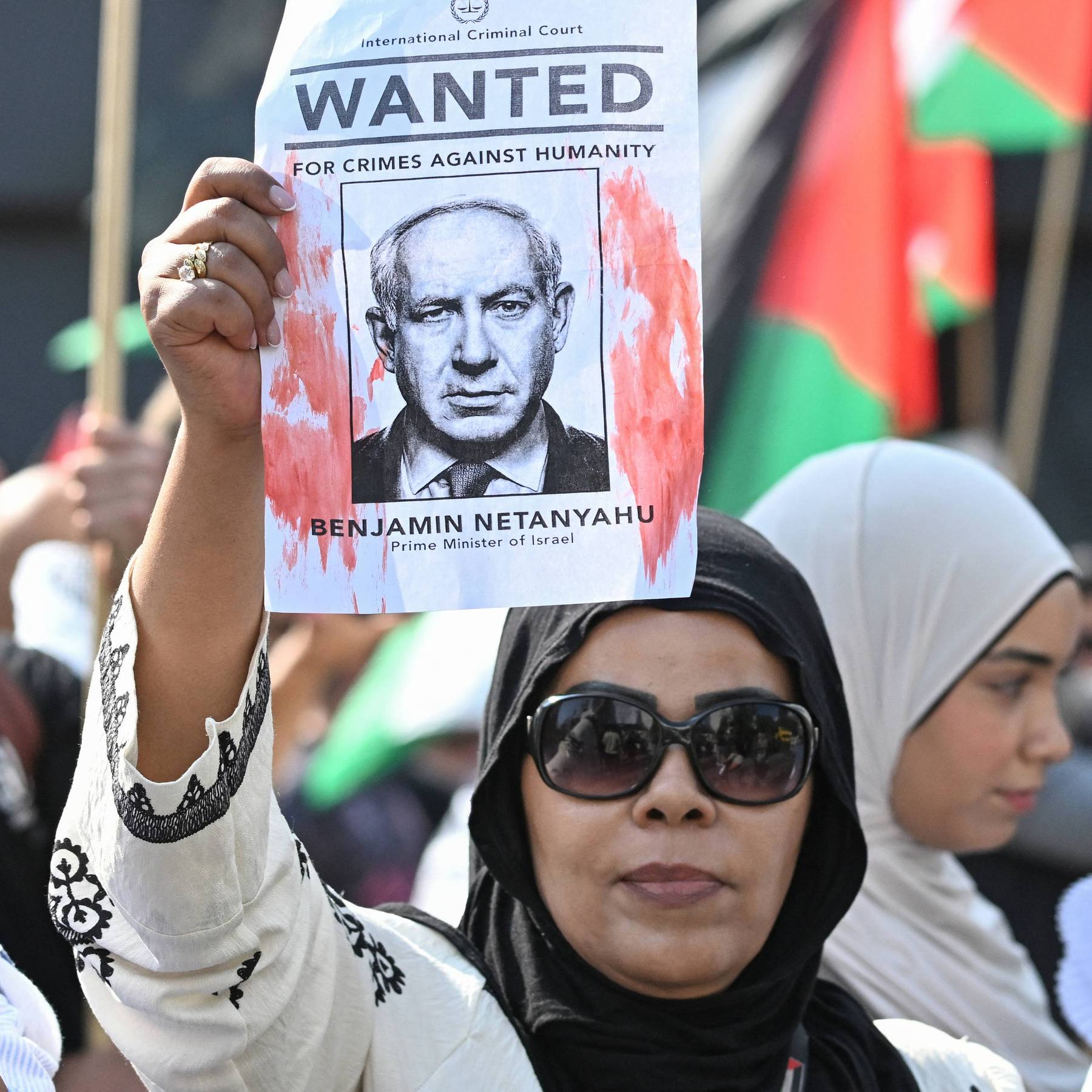 A demonstrator holds up a "Wanted" poster featuring Israeli Prime Minister Benjamin Netanyahu