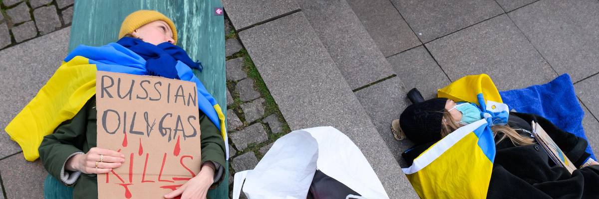 A demonstrator lies on the Rathausmarkt and holds a sign with the inscription "Russian Oil & Gas kills" in Hamburg, Germany on April 9, 2022. (Photo: Jonas Walzberg/dpa via Getty Images)