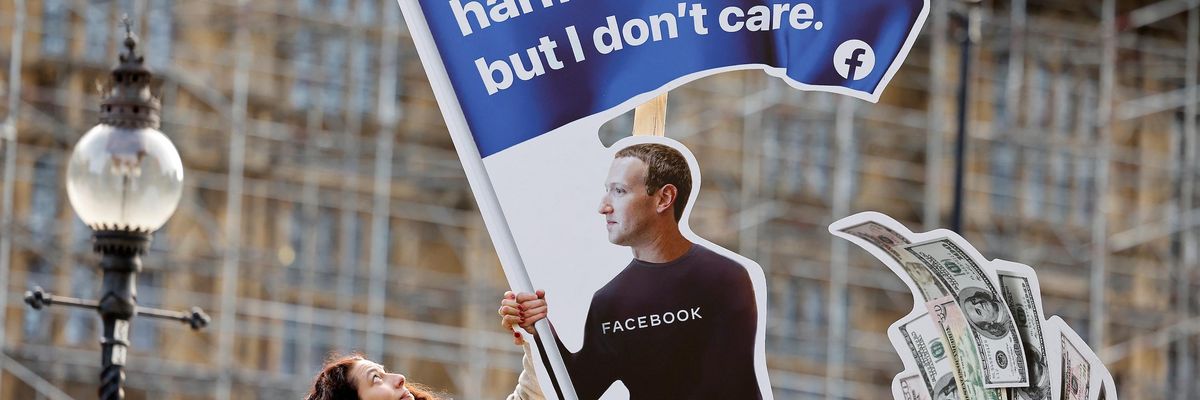 A demonstrator poses with an installation depicting Facebook founder Mark Zuckerberg surfing on a wave of cash and surrounded by distressed teenagers, during a protest opposite the Houses of Parliament in central London on October 25, 2021, as Facebook whistleblower Frances Haugen is set to testify to British lawmakers. (Photo by Tolga Akmen / AFP)