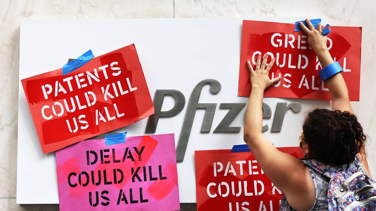 A demonstrator tapes signs to Pfizer headquarters