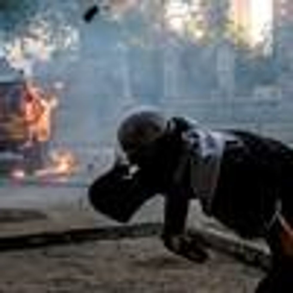 A demonstrator throws stones at a police vehicle during a protest against extreme economic inequality in Santiago, Chile on November 29, 2019. (Photo: Martin Bernetti/AFP via Getty Images)