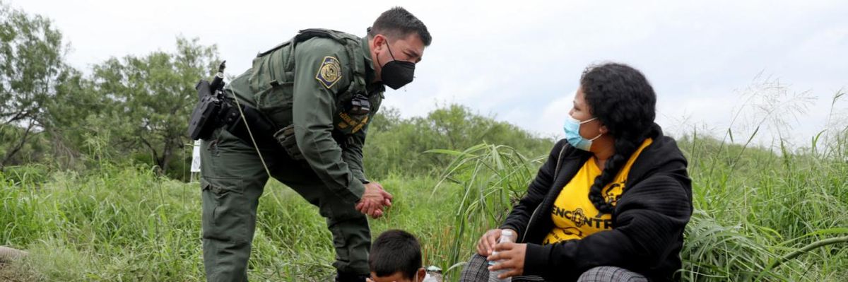 A DHS agent talks to a woman and her child after they crossed into the U.S. from Mexico