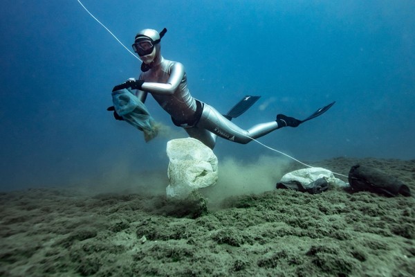 A diver removes plastic from the ocean floor.