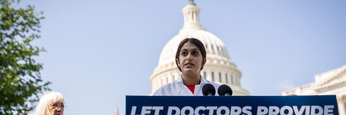 A doctor stands with a sign reading, "Let doctors provide reproductive healthcare"