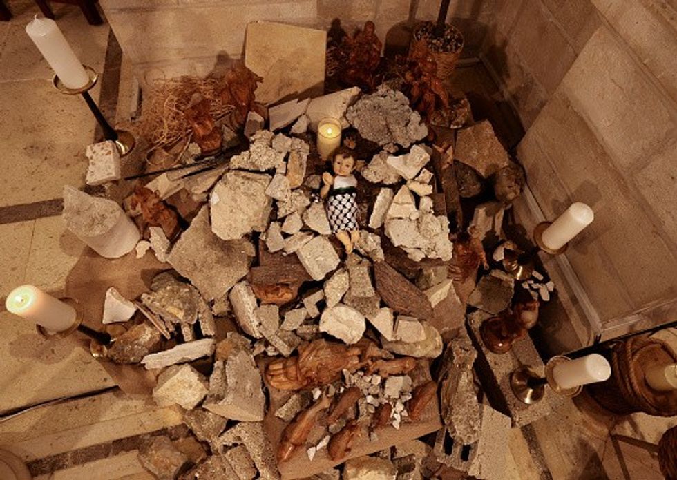 A doll representing baby Jesus lies in a manger amidst rubble in Bethlehem