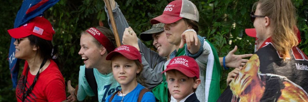 A family in MAGA hats waves a flag.