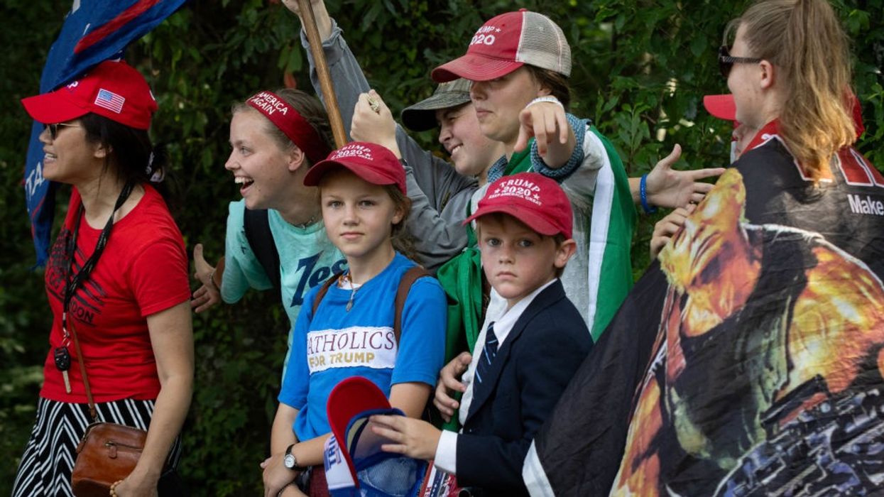 A family in MAGA hats waves a flag.