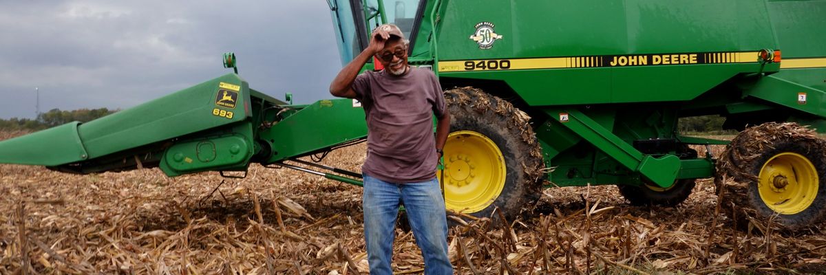 A farmer stands in front of a tractor.